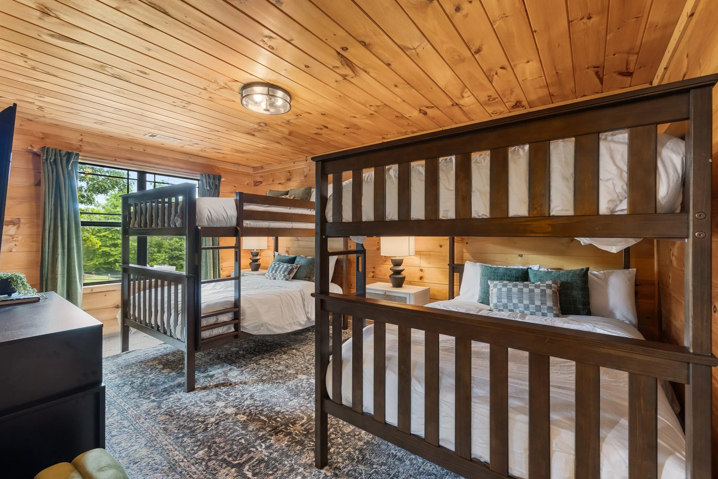 Upstairs bunk room with two sets of full-size wooden bunk beds and a window