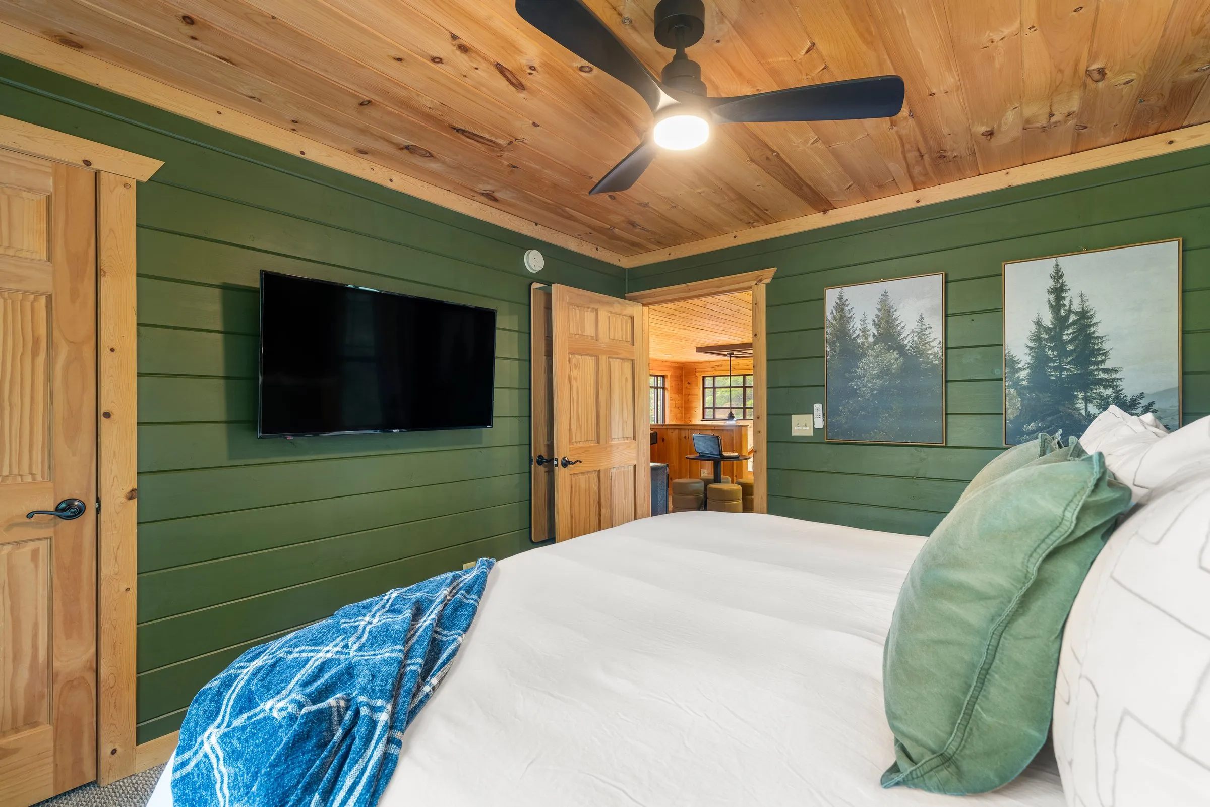 Bedroom 3 with a king bed, green shiplap walls, television and a ceiling fan