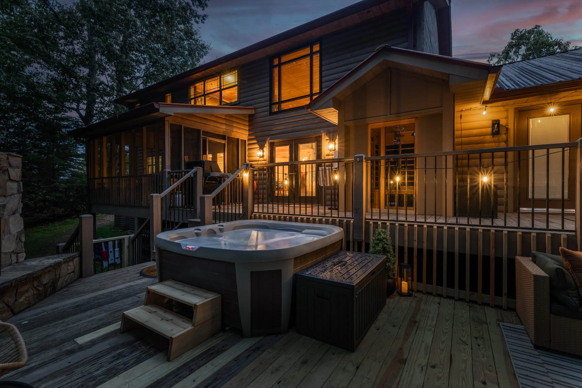 Back deck at dusk with hot tub, sectional sofa and lantern lighting