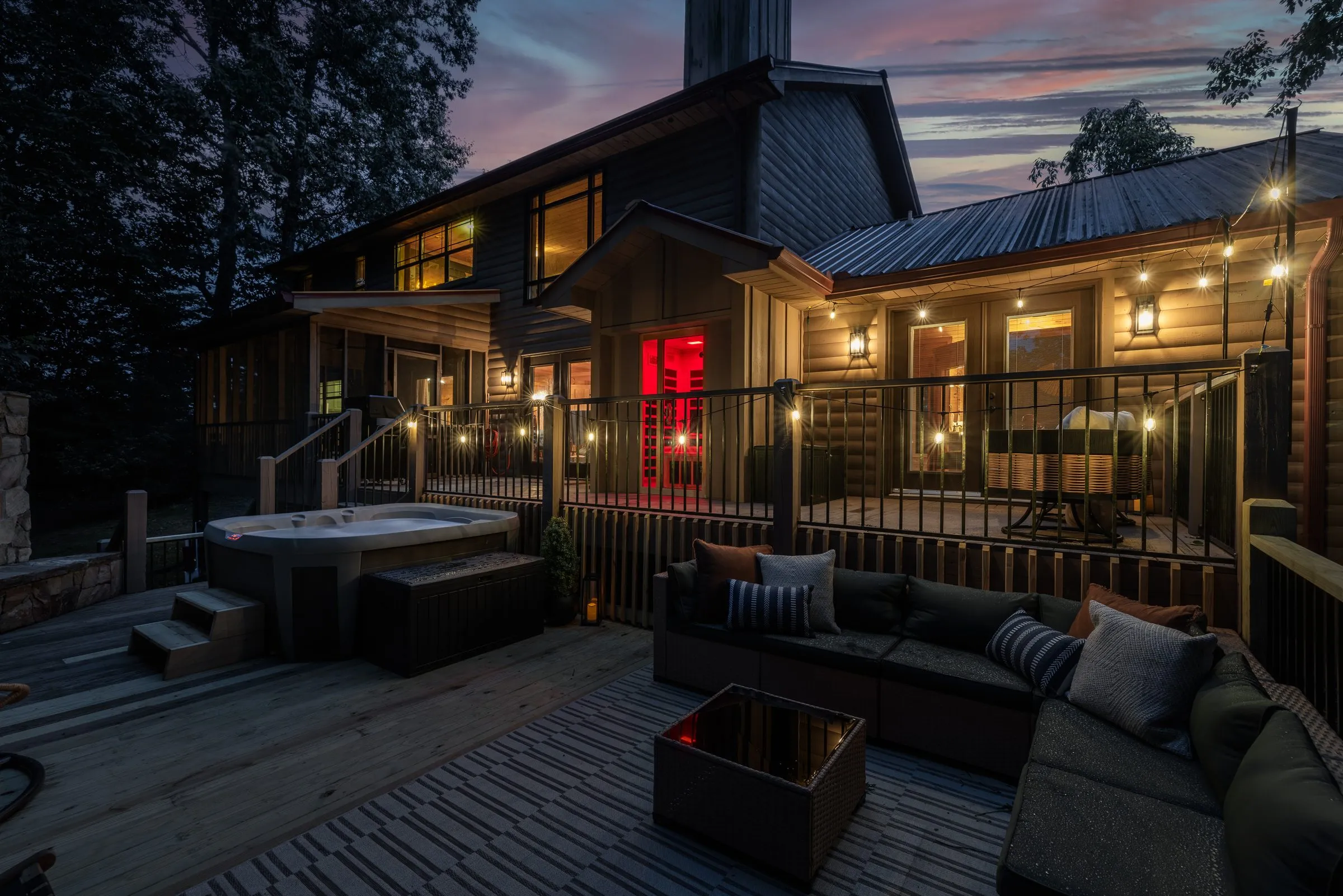 Back deck at night with the hot tub and the infrared sauna glowing red
