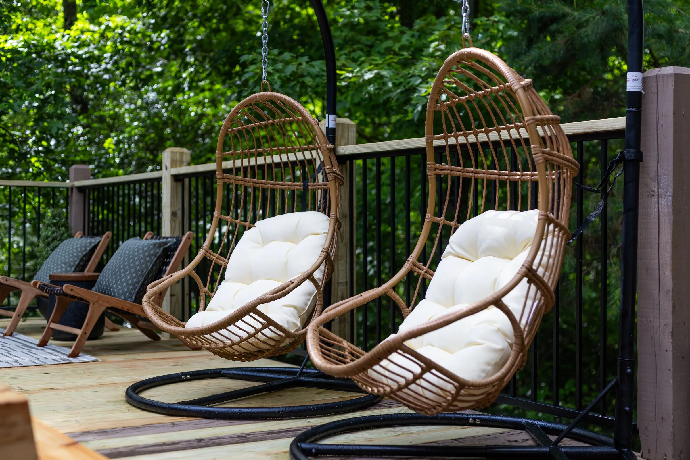 Two hanging egg chairs with cream cushions on the deck