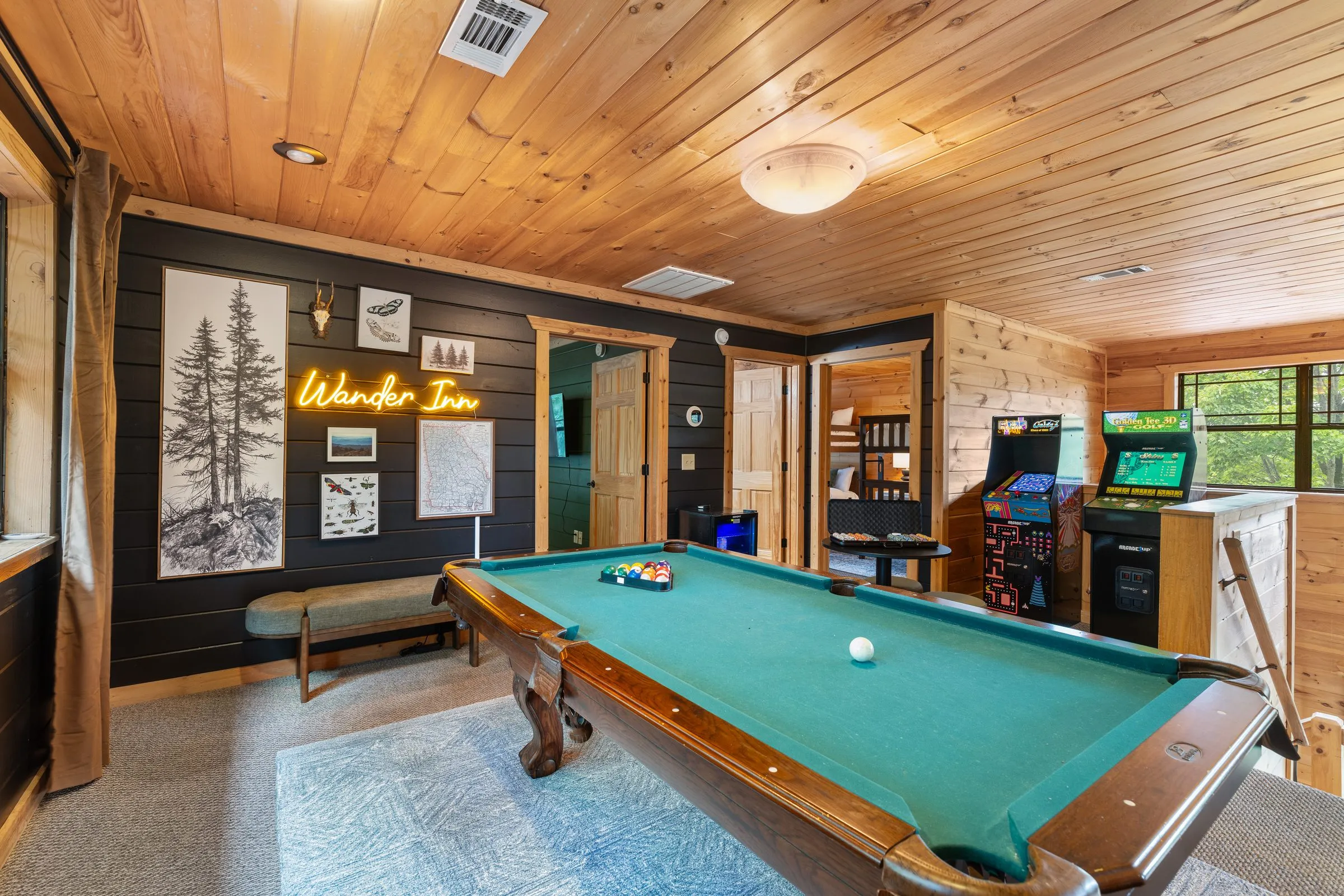 Wide view of the game room with pool table and arcade cabinets