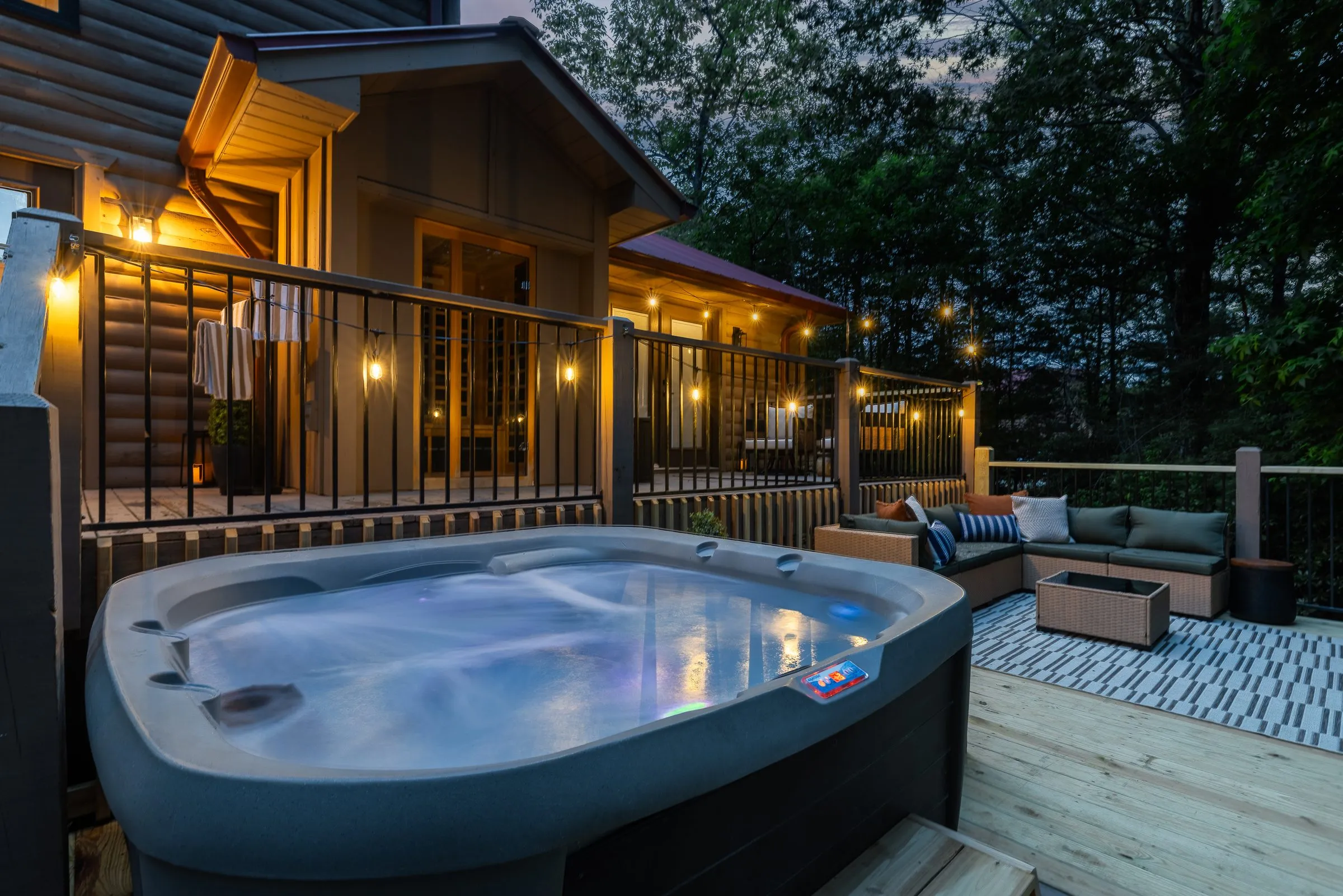 Steaming private hot tub on the back deck at dusk with a sectional sofa