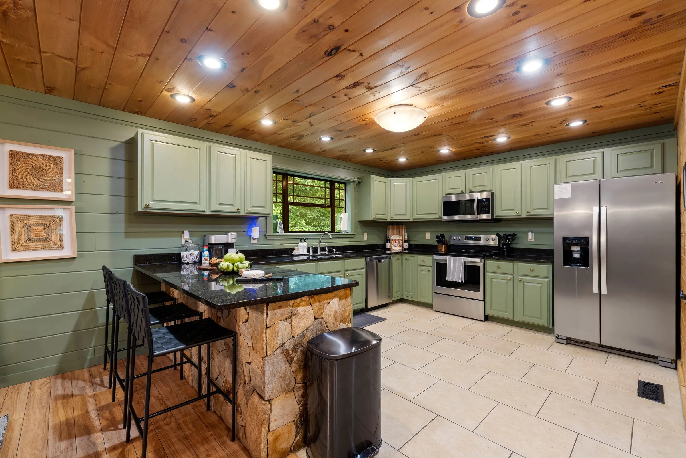 Fully stocked kitchen with sage green cabinets, island and stainless appliances