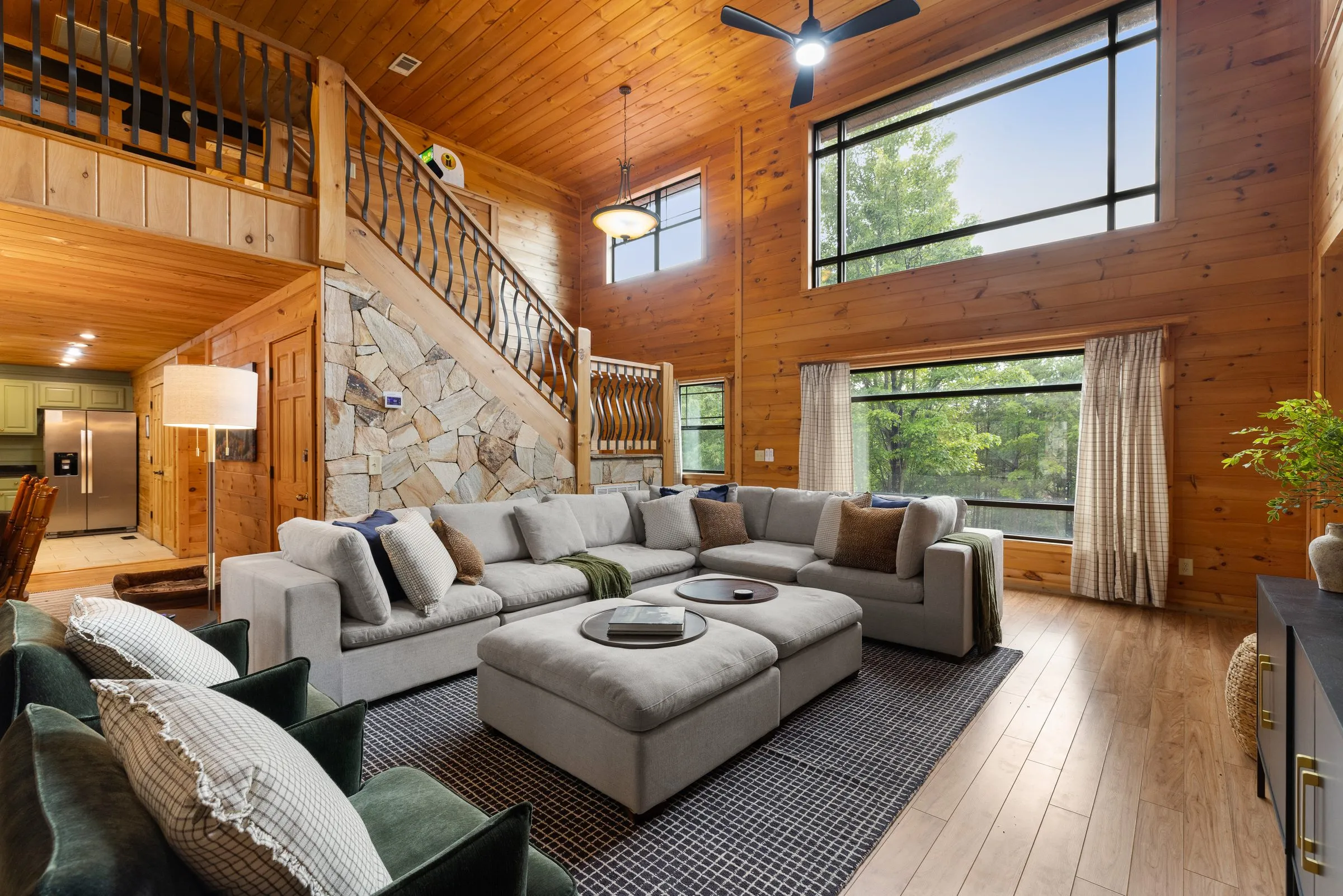 Vaulted living room with tall windows, stone staircase wall and sectional