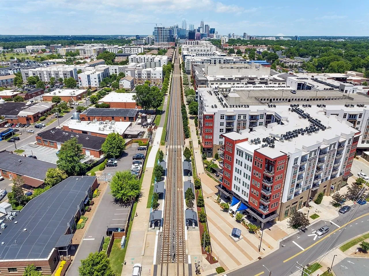 Aerial view of the light rail line and Rail Trail running toward the Charlotte skyline in South End