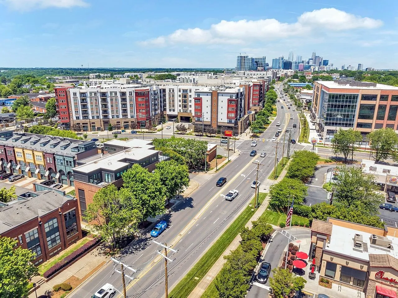Aerial view of South End, Charlotte, with shops, restaurants and apartment buildings along the main street and the city skyline beyond