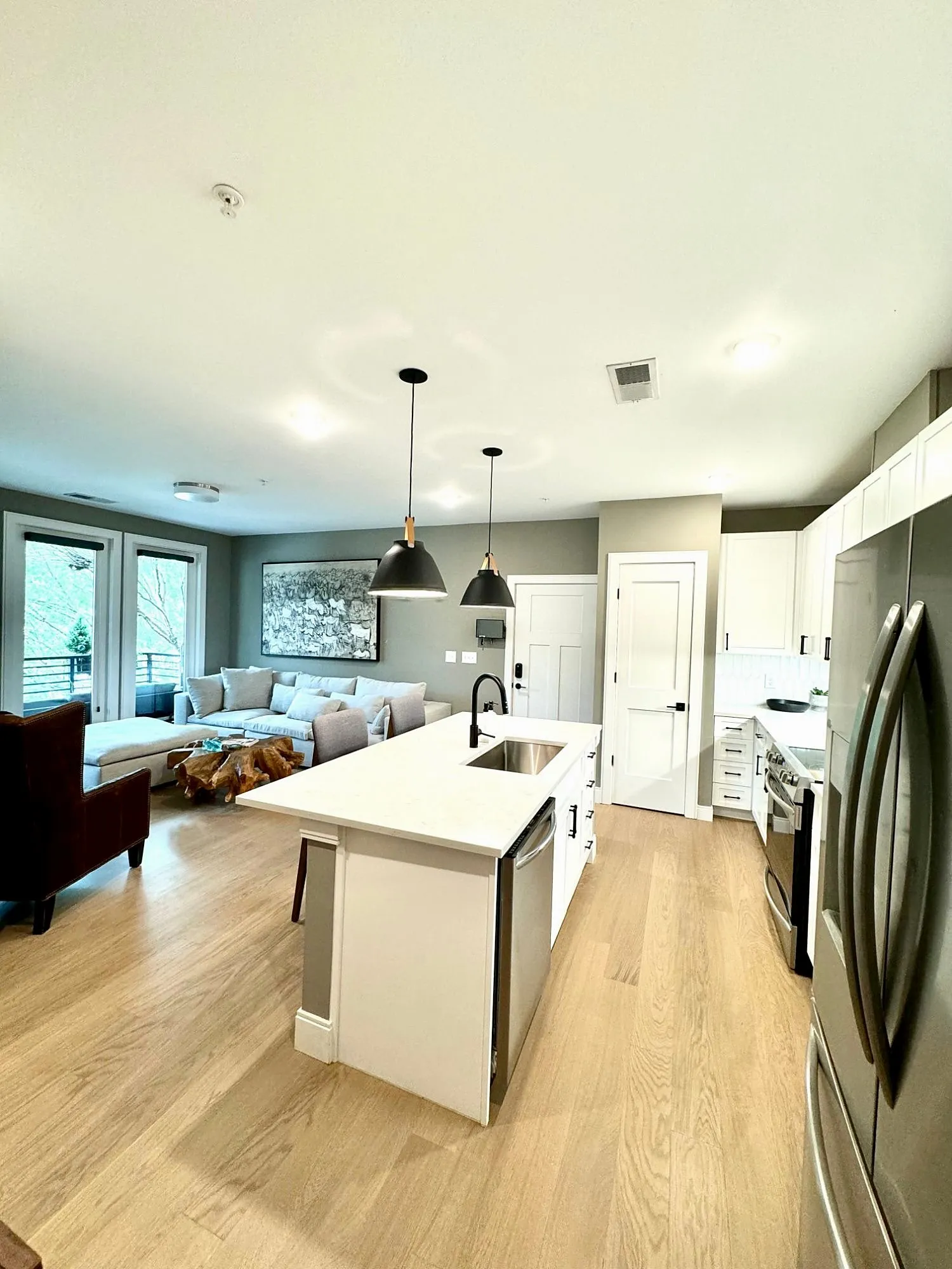 Open-plan living and kitchen with an island, oak floors and glass doors to the patio