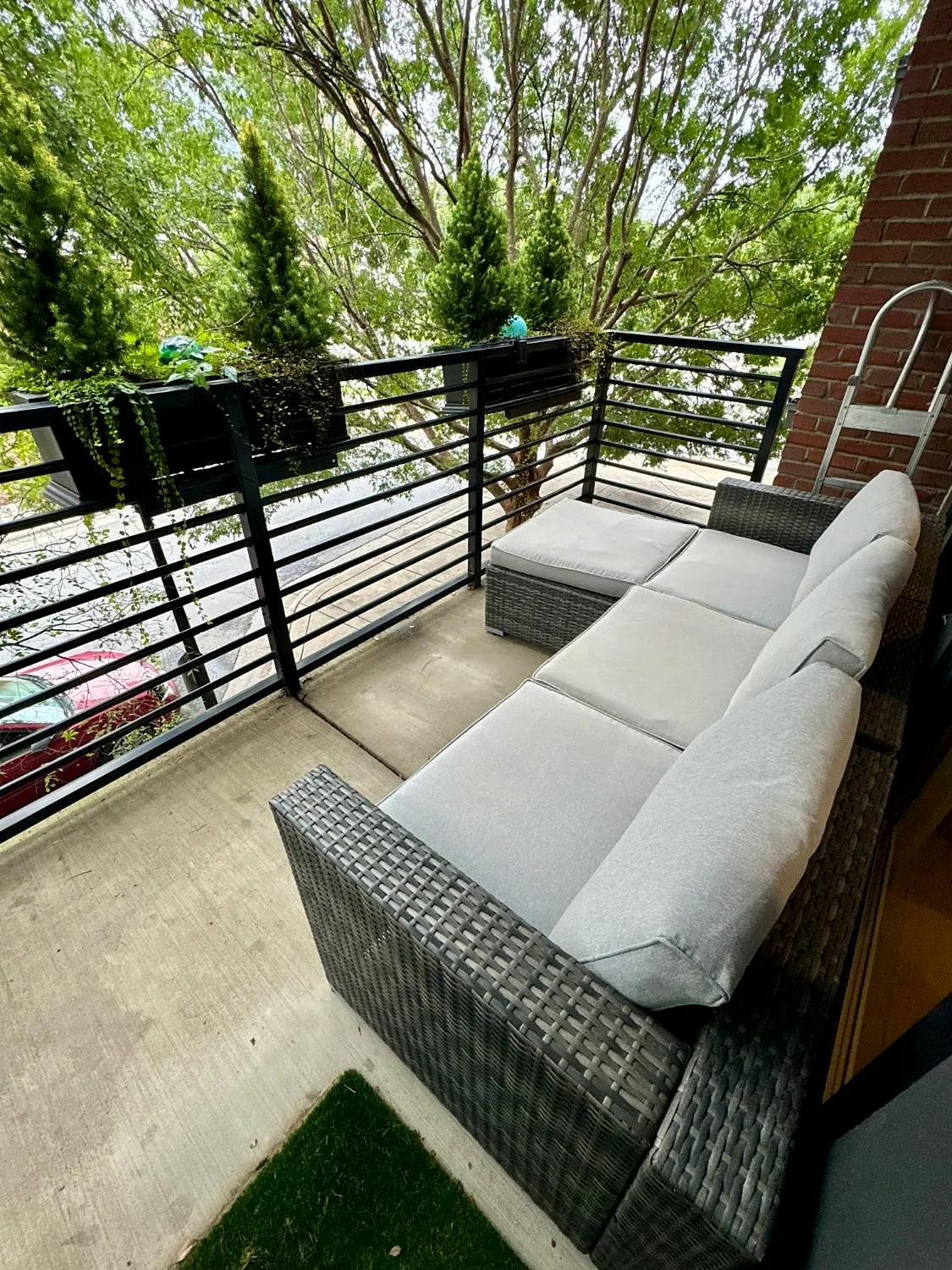 Private covered patio with a gray outdoor sectional, planter boxes and leafy trees